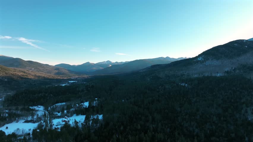 Aerial view of the Adirondack Mountains in New York during winter, with snow-covered forests.