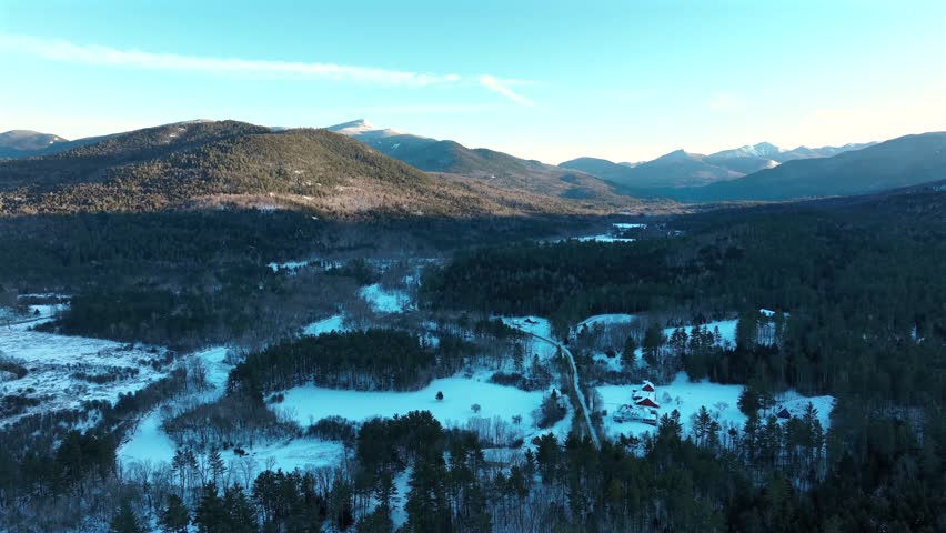 Aerial view of the Adirondack Mountains in New York during winter, with snow-covered forests.