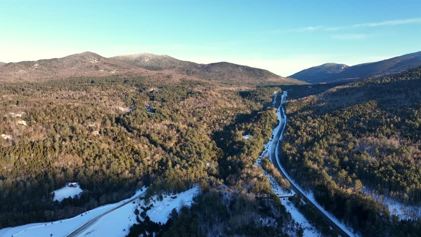 Aerial view of the Adirondack Mountains in New York during winter, with snow-covered forests.