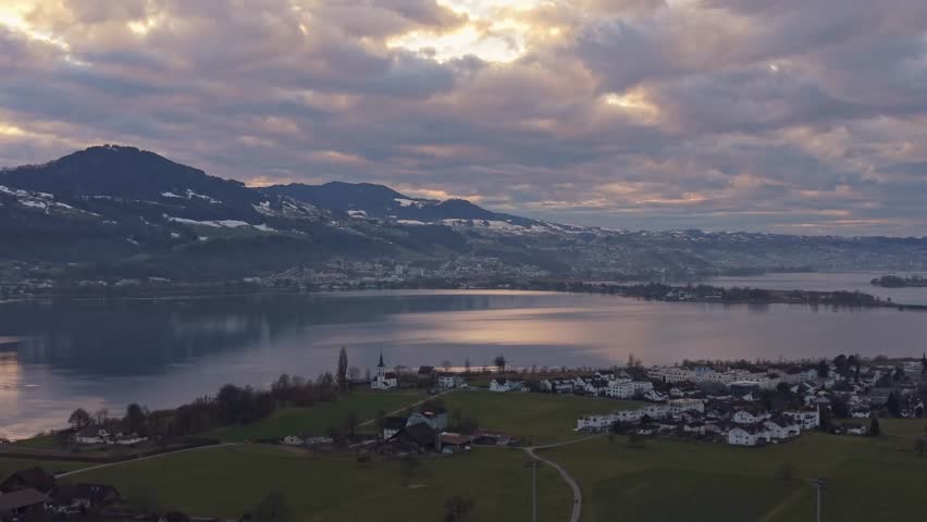 Aerial landscape of Lake Zurich, majestic mountain range and sunset glow over the water.