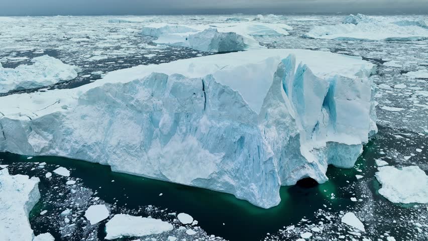 Aerial view of massive iceberg near Ilulissat in Greenland at Disko Bay. Drone footage over Greenland shows drifting ice formations in cold Arctic waters near Ilulissat