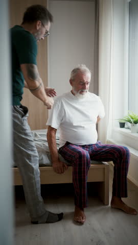 Son supporting father after surgery, helping him to recover.