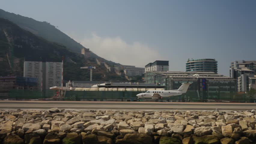 Private airplane departing gibraltar international airport runway with the rock of gibraltar, buildings, and clear sky in the background