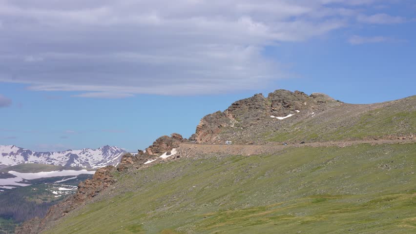Multiple cars driving along the most scenic section of Trail Ridge Road in Rocky Mountain National Park, Colorado. Breathtaking mountain landscapes and winding alpine roads showcasing the beauty of this iconic national park.