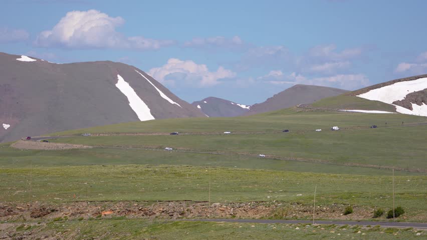 Beautiful scenic view of mountains in the background as a car drives in a zig-zag pattern along Trail Ridge Road in Rocky Mountain National Park, Colorado