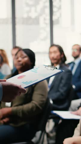 Vertical Video Multiethnic people asking questions and raising hand during discussion, engaging in debate and listening to convention speech. Diverse group of white collar workers attend event. Camera