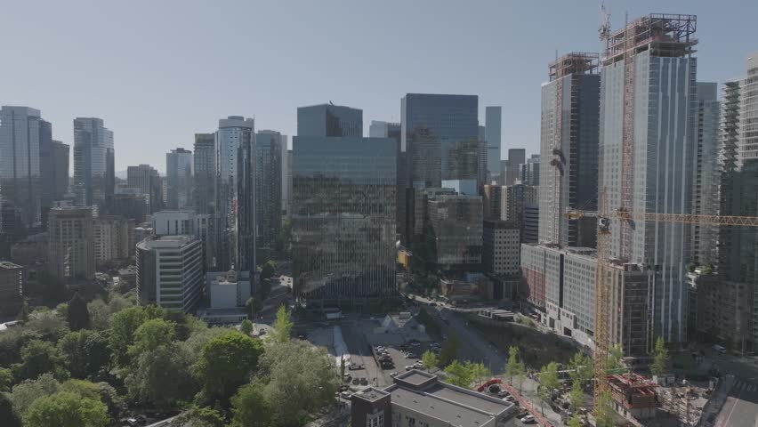 Aerial view of downtown Seattle skyscrapers and active construction with trees and streets below under a clear sky, showcasing urban development and modern city architecture
