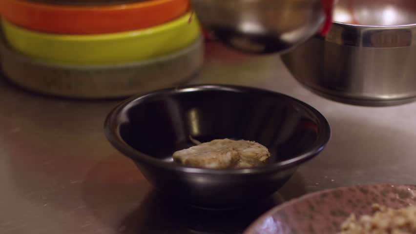 Serving borsch. Portioned dish. Pouring hot red liquid meal in black bowls. Chef hand scooping traditional beet soup on restaurant kitchen table.