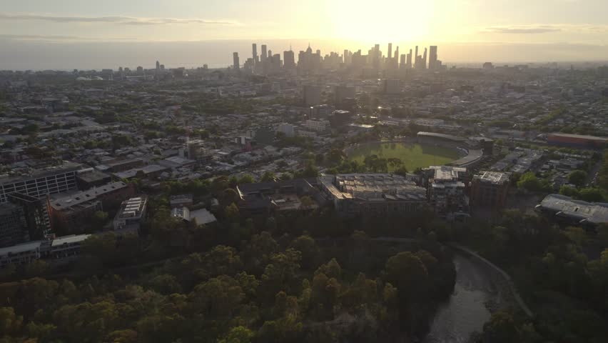 Reversing aerial view at sunset of the Yarra River in the foreground and the Mebourne city skyline in the distance, Victoria, Australia. December 2025