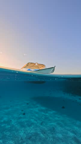 Vertical Half Underwater View of Tropical scene With Anchored Fishing Boat In clear transparent blue sea