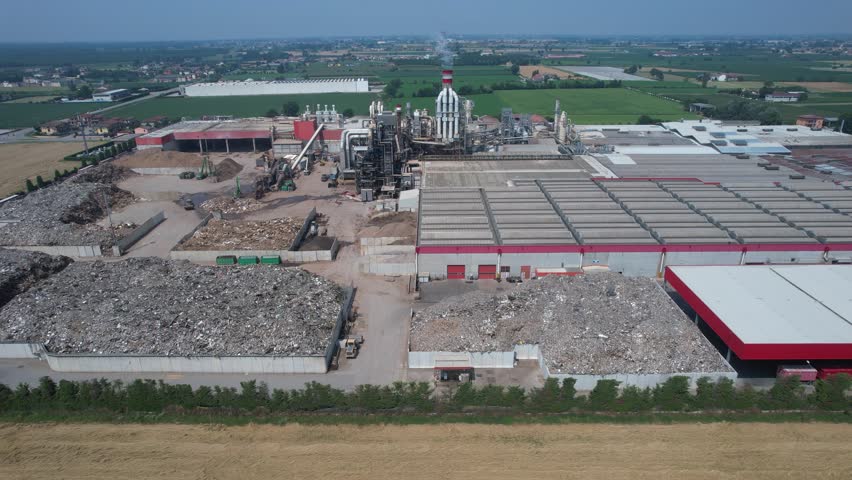 drone view of an integrated cement manufacturing plant showing rotary kiln line, preheater tower, clinker cooling system, raw material storage yards and heavy industrial processing infrastructure.