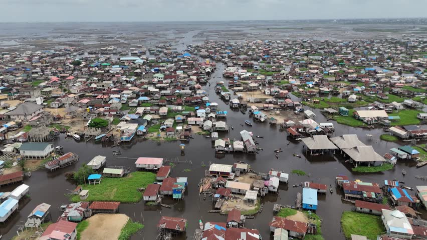 A wide aerial angle of Ganvie, the largest floating village in Africa, showcasing the dense network of stilt houses and traditional boats