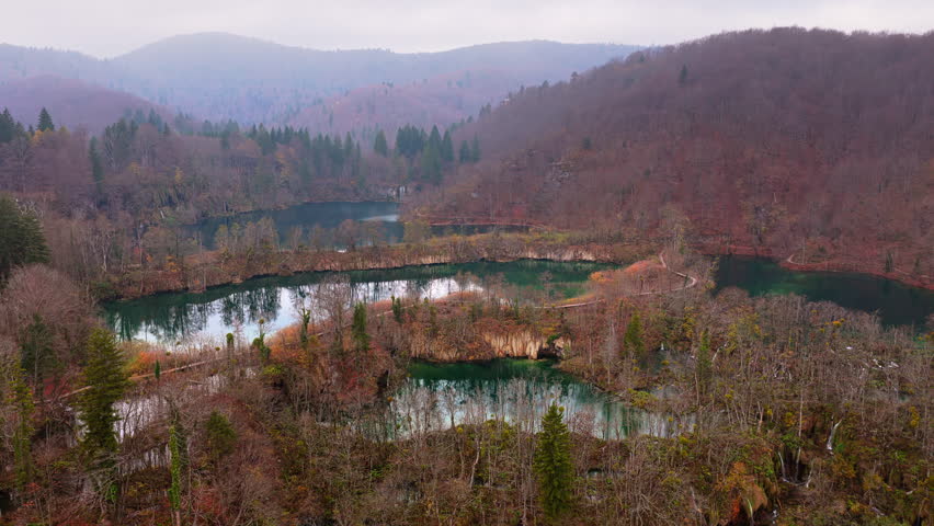 Aerial drone view of fog covered turquoise lakes separated by narrow forested islands at Plitvice Lakes, Croatia