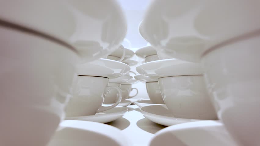 White porcelain tea cups with saucers stacked in rows creating a symmetrical pattern
