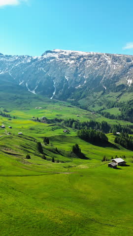 Alpe di Siusi fields with chairlift lines and small farm buildings, aerial view. Mountain plateau within the Dolomites of Italy