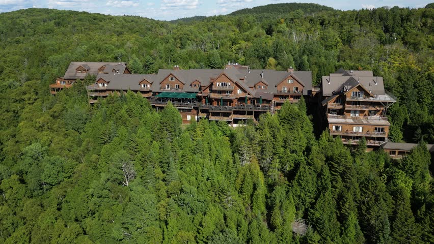 Aerial reveals Hotel Sacacomie nestled in forest beside lake in remote Quebec wilderness