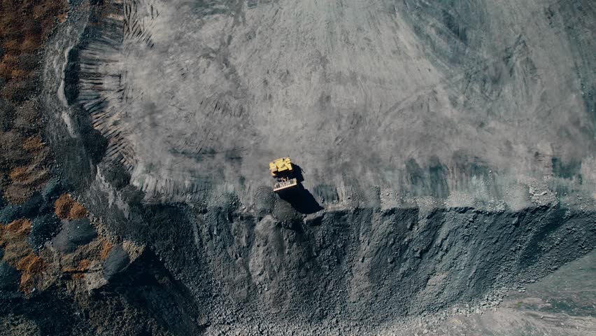 Open pit mine with unloading dump truck, extractive industry for coal, top view aerial.