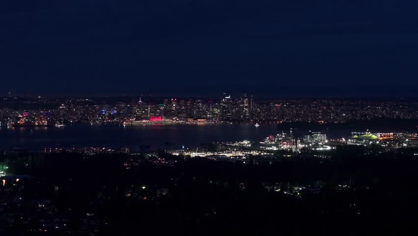 Nighttime view of Vancouver’s downtown skyline seen from Norwood Avenue, with city lights reflecting across the water and creating a calm, cinematic urban atmosphere.