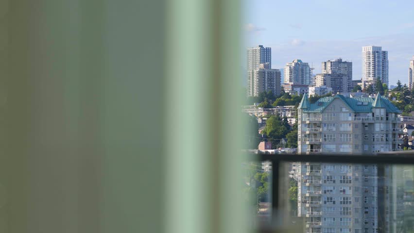 Daytime view of New Westminster skyline with modern high-rise buildings and green neighborhoods, seen from a residential apartment balcony
