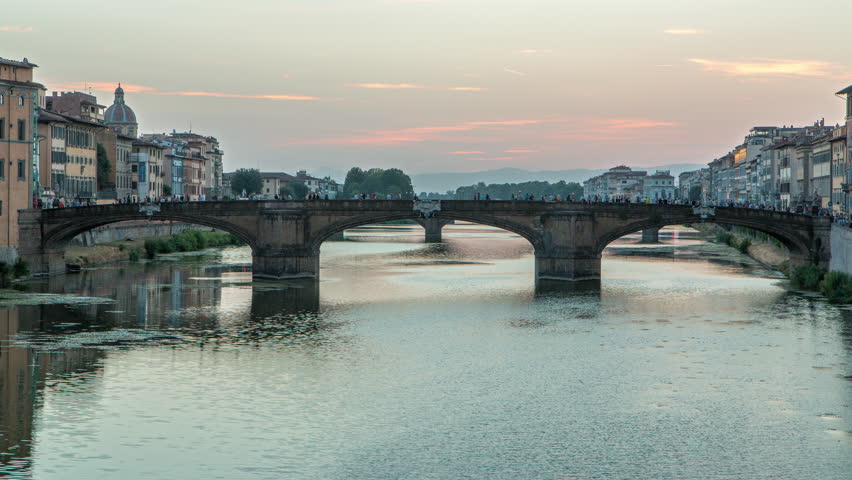 Twilight scene of Ponte Santa Trinita (Holy Trinity Bridge) day to night transition timelapse over River Arno with reflections on water after sunset. Florence, Tuscany, Italy