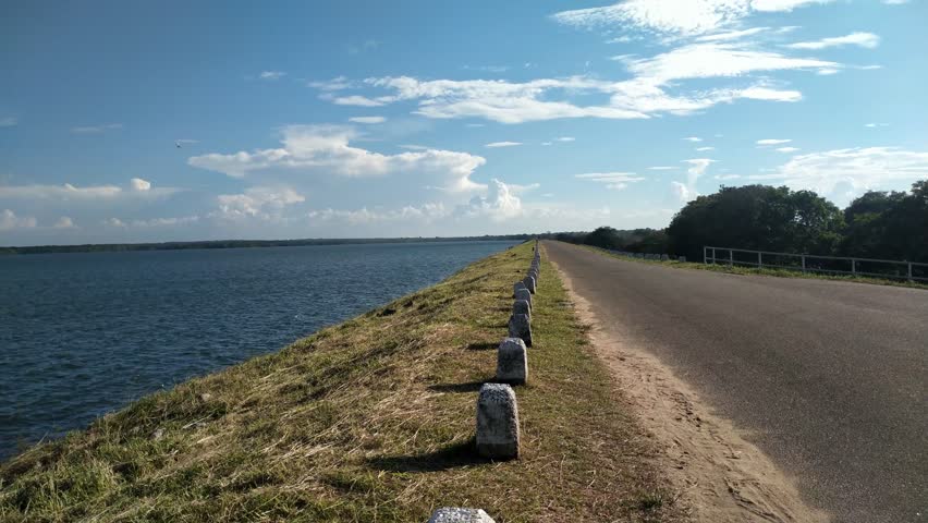 Scenic Road Alongside Vast Blue Lake Under Cloudy Sky