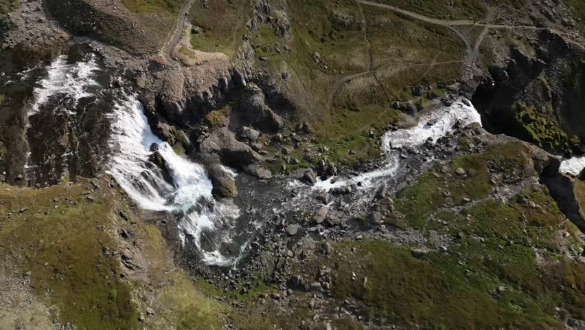 Dramatic drone shot of a white water river flowing through rocky mountain terrain. Ideal for travel documentaries and nature conservation videos.