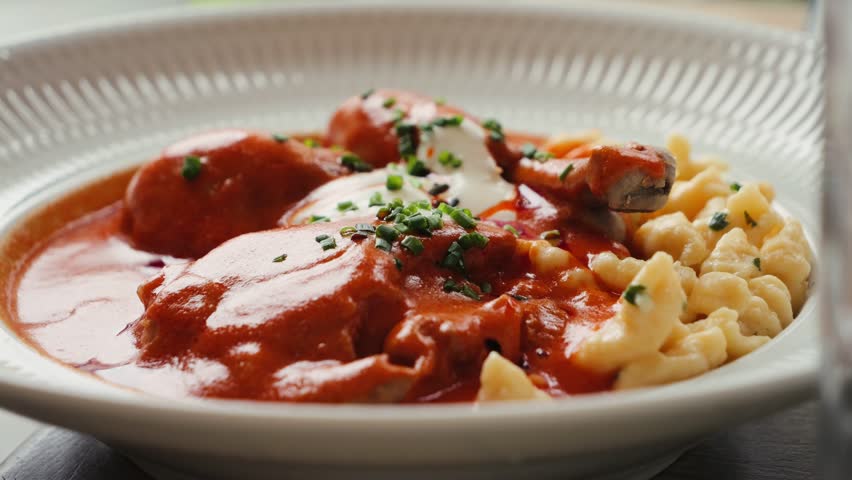 Traditional Hungarian goulash with tarhonya garnished with a sprig of parsley.