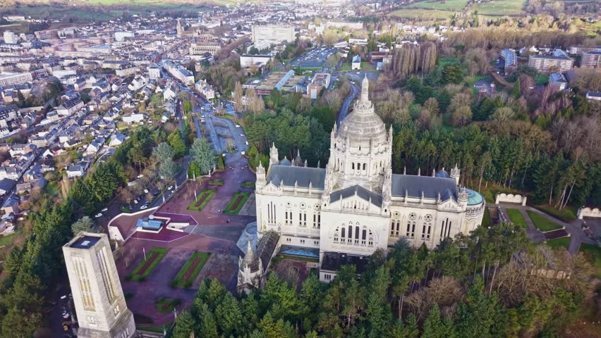 Aerial view of the Basilique Sainte Thérèse in Lisieux city, Calvados county, Normandy region, showing the monumental sanctuary surrounded by wooded park, pilgrimage gardens and historic district.