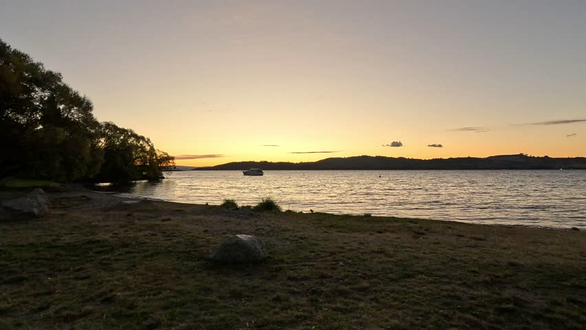 Tranquil shoreline view of Lake Tekapo during golden hour. Serene water movement and alpine sunset colors