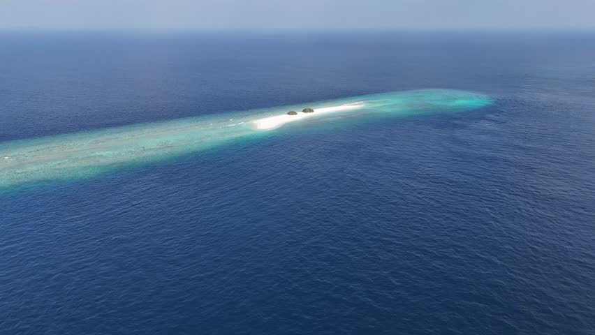 Aerial drone view of remote sandbank island in Maldives surrounded by turquoise lagoon