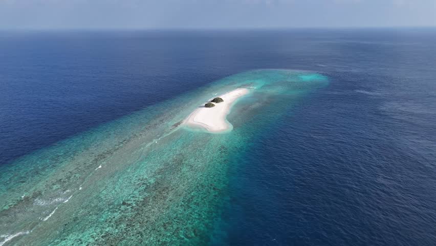 Aerial drone view of remote sandbank island in Maldives surrounded by turquoise lagoon