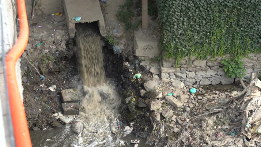 A dirty underground sewage exit with flowing water.