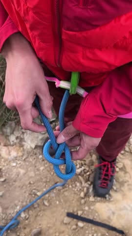 Tying a figure eight knot to a climbing harness with rope