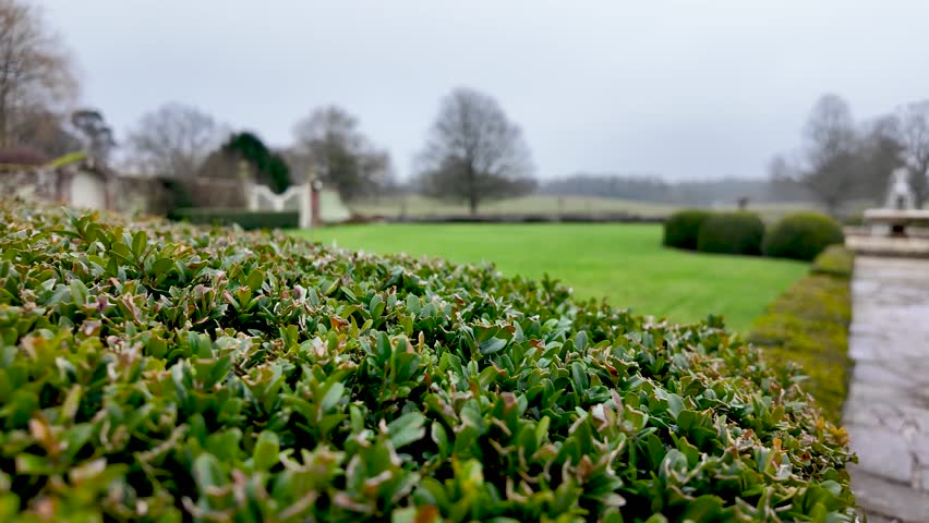 Formal Garden With Green Hedge And Lawn At Stately Home In England Featuring Trees And Distant Architecture On An Overcast Day Landscape Design.