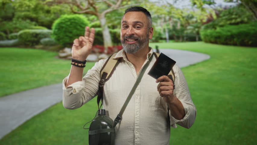Middle aged hispanic man holding passport and showing three fingers in green park with backpack and canteen; adventure.