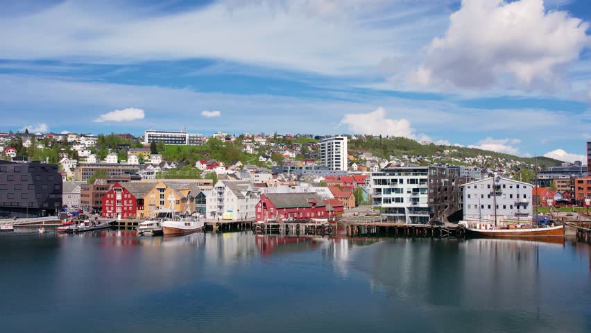 Soaring above the Norwegian city of Troms in the rays of the midnight sun. Picturesque city waterfront, ocean fjord, and a unique blend of urban life and Arctic wilderness. Sea cruises