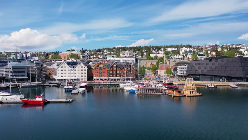 Soaring above the Norwegian city of Troms in the rays of the midnight sun. Picturesque city waterfront, ocean fjord, and a unique blend of urban life and Arctic wilderness. Sea cruises