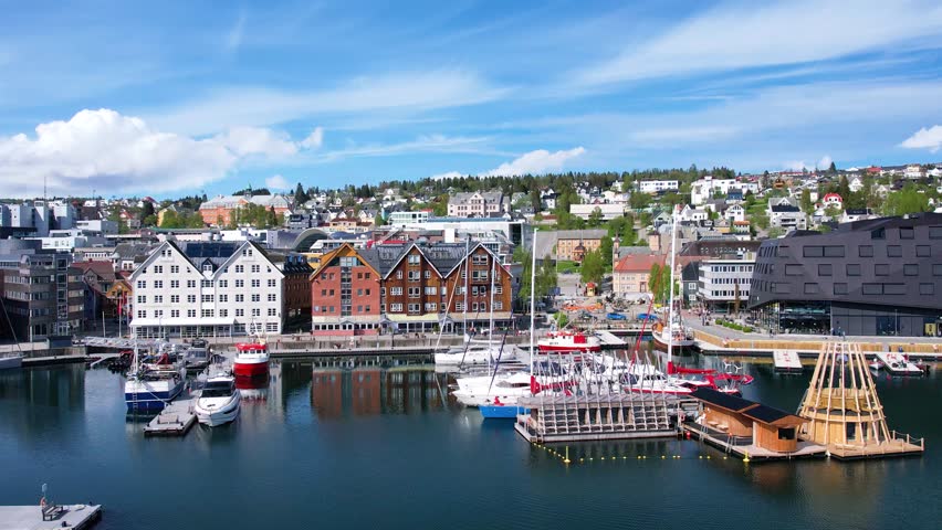 Soaring above the Norwegian city of Troms in the rays of the midnight sun. Picturesque city waterfront, ocean fjord, and a unique blend of urban life and Arctic wilderness. Sea cruises
