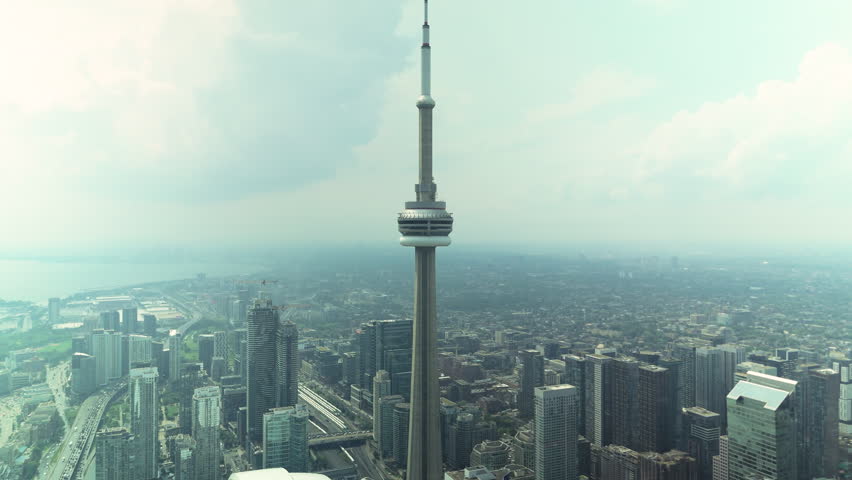 Aerial drone view of CN Tower and Toronto skyline on rainy cloudy day with panoramic urban cityscape and waterfront perspective from high altitude