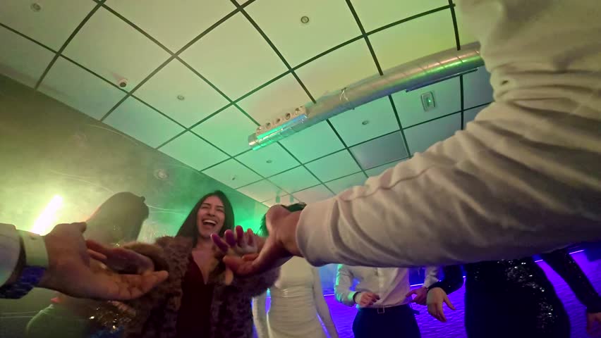 First person perspective of a person dancing with happy friends in a crowded nightclub with colorful strobe lights, enjoying the music and celebrating together during a fun night out