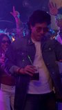 Cool young man in a denim jacket and sunglasses holding a cocktail while dancing with friends at a nightclub party with colorful neon lights, having a great time during a vibrant evening out - Powered by Shutterstock - Get 15% off with code: PIKWIZARD15