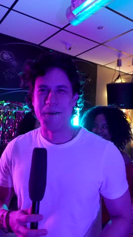 Happy diverse friends singing into a microphone and dancing at a lively karaoke party, enjoying the music and vibrant neon lights of a nightclub while celebrating together