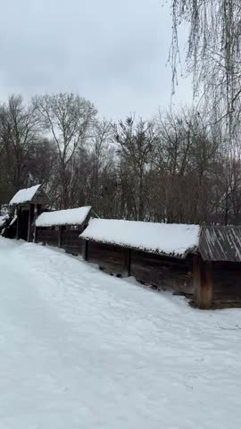 An ancient Ukrainian wooden church with snow-covered domes and a fence in a winter landscape of the 18th–19th centuries.