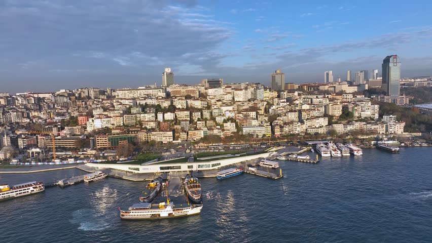Panoramic drone view of Istanbul showing Dolmabahce Palace and the Bosphorus coastline, mosques, waterfront houses, narrow streets. A mix of historic Ottoman architecture and a modern city skyline