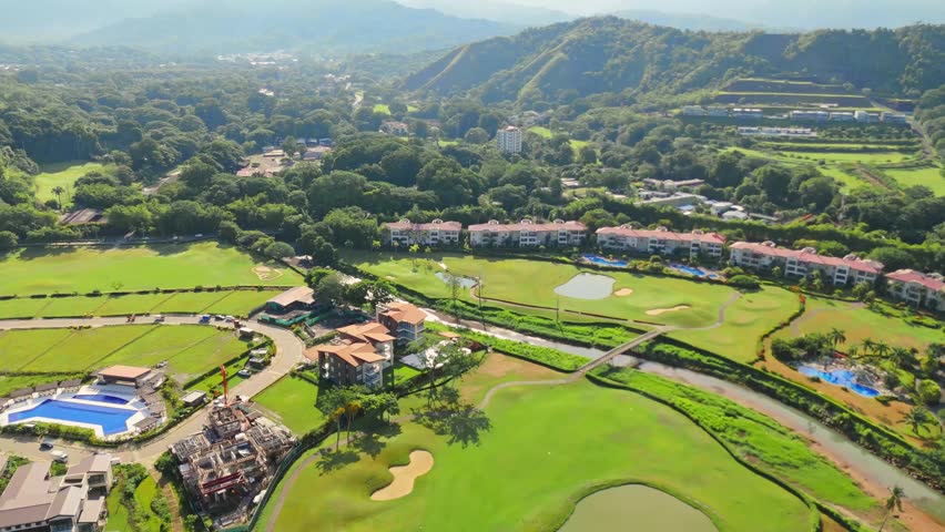 scenic drone panorama of a luxury resort with golf courses, swimming pools, and tropical landscapes