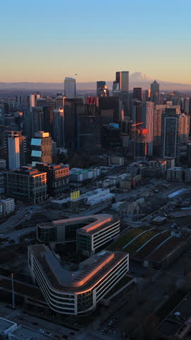 Panoramic aerial of Seattle Washington skyline and coastal bay, captured during golden hour showing city scale and Mount Rainier, layered neighborhoods and modern urban form. USA