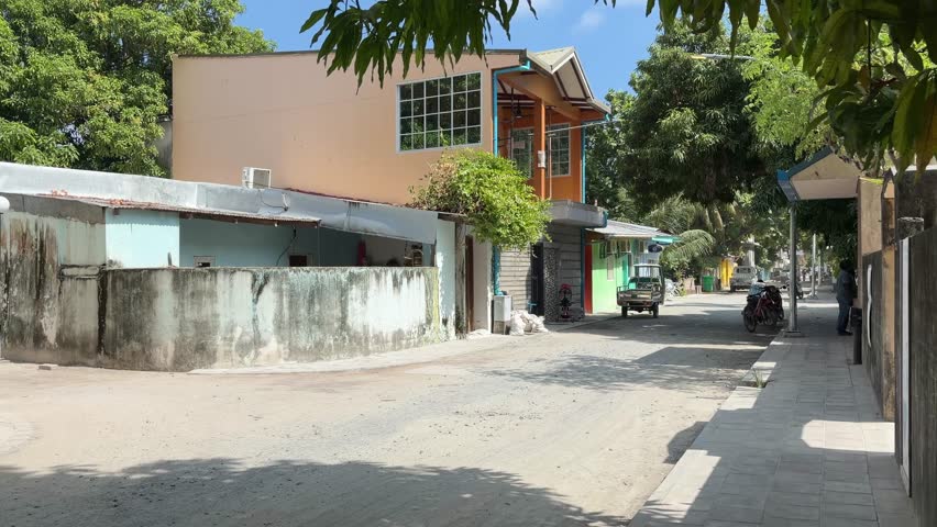 Quiet sandy street in Ukulhas Maldives lined with palm trees and island houses