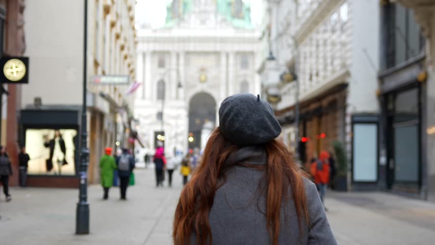 Woman in gray coat walking in Vienna shopping street