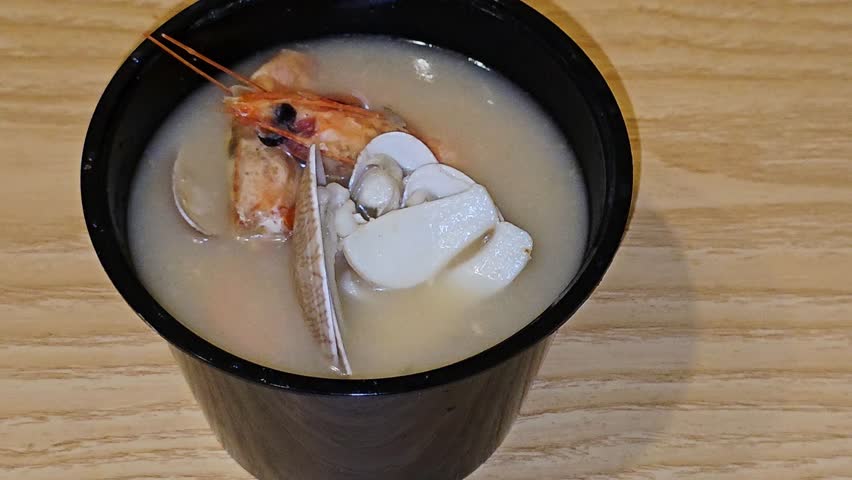 assorted seafood creamy soup of shrimps, squid, crabs, fish fillet, herbs, dill, garlic and onion, seafood mixture hot soup, healthy food concept of pieces of various sea food, selective focus