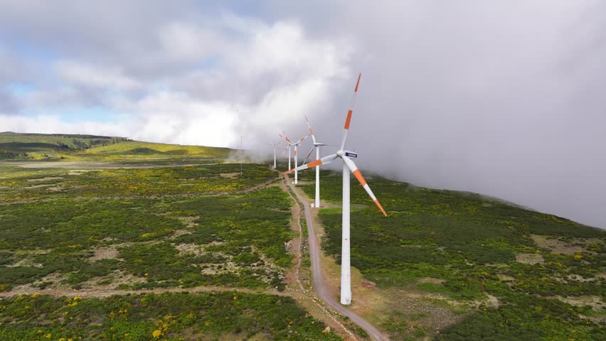 Aerial view of wind turbines rotating in lush Madeira landscape in misty weather